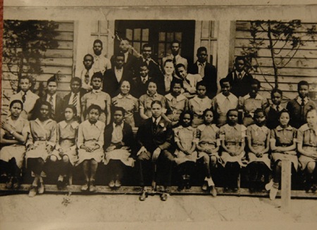 RCTS 8th graders pose in front of the 1919 RCTS building for  with Principal E. S. Peoples in 1940. Female students are wearing their required school uniforms.