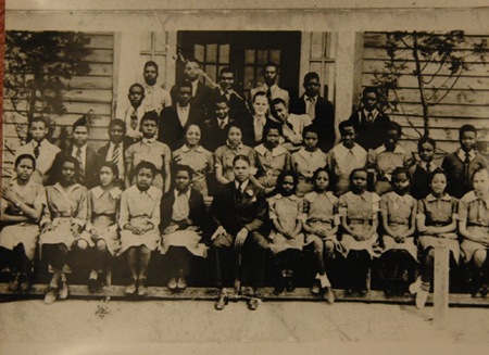 RCTS 8th graders pose in front of the 1919 RCTS building for with Principal E. S. Peoples in 1940. Female students are wearing their required school uniforms.
